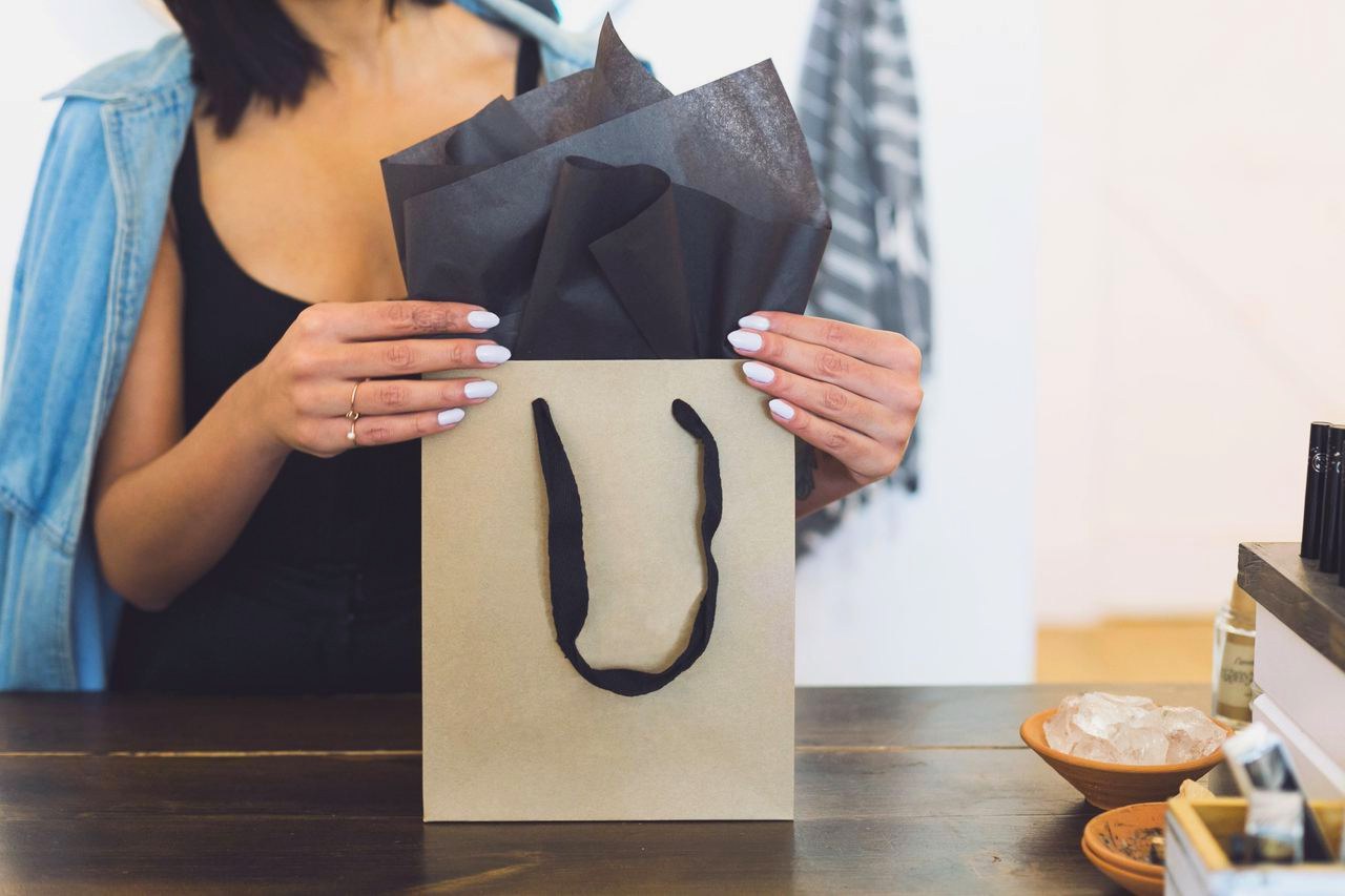 A shop assistant tucking tissue into a gift bag at a boutique counter