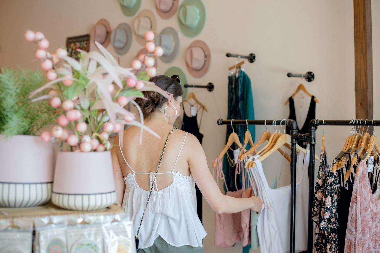 A shopper browsing a rail of tops in a boutique