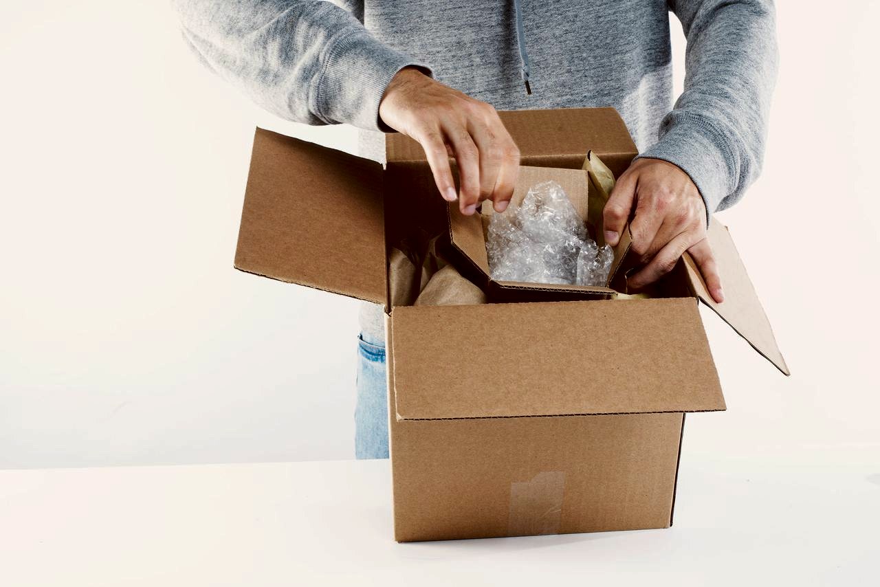 Hands packing an order into a shipping box