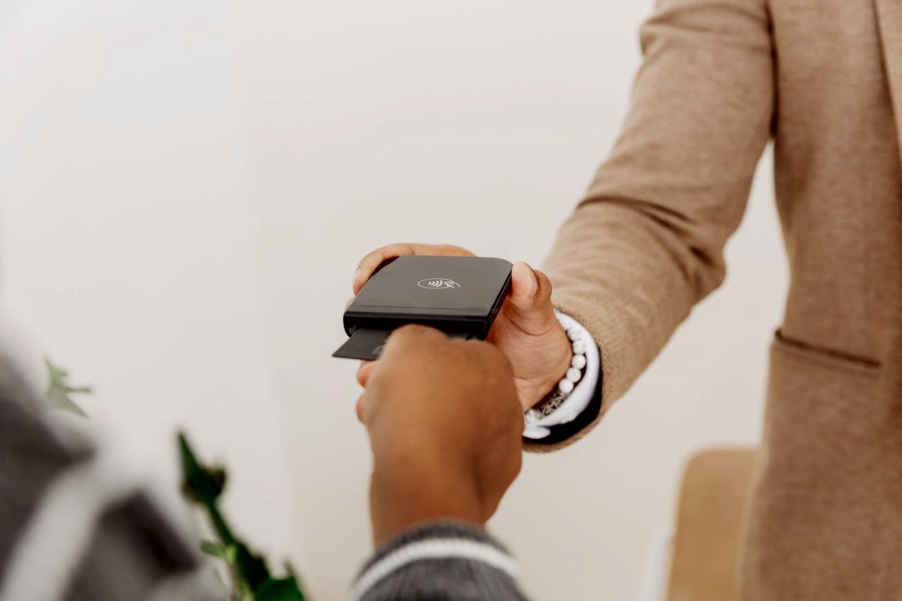 A customer inserts a card into a Shopify Tap and Chip Card Reader held out by a shop associate